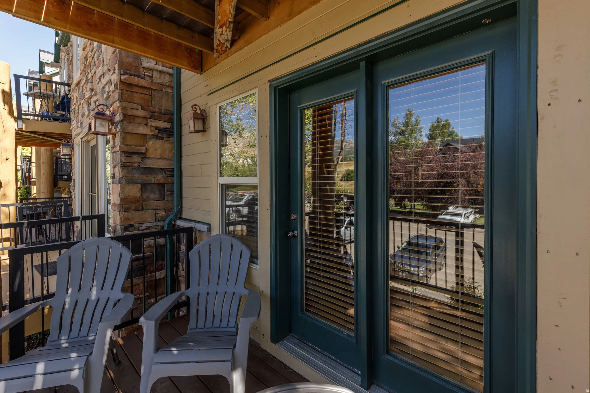 Balcony featuring stacked stone accents, wood-finish flooring, and a dark-paneled glass door