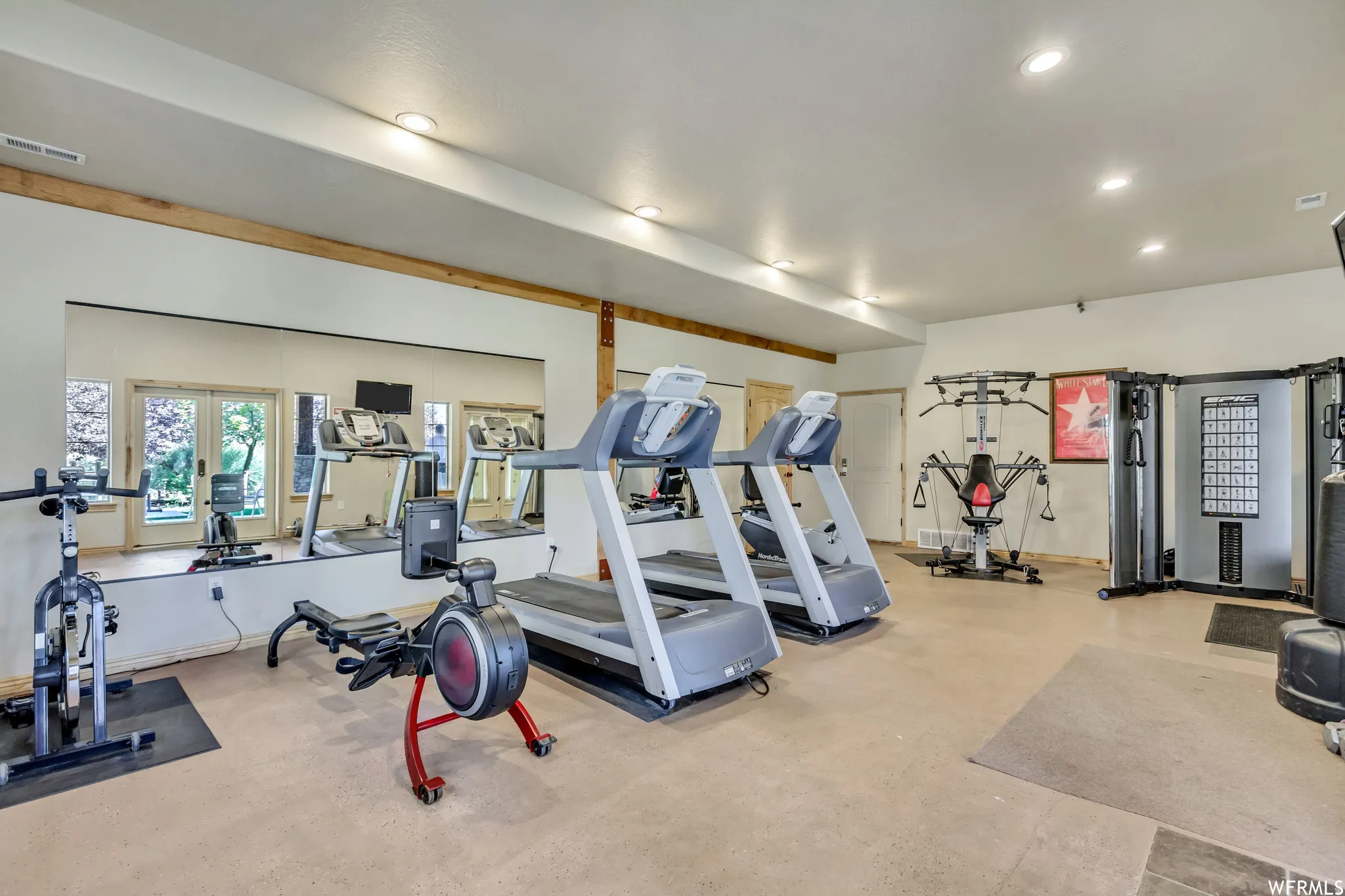 Dedicated fitness space featuring recessed lighting, exposed wood beams, wall-mounted mirrors, and durable flooring