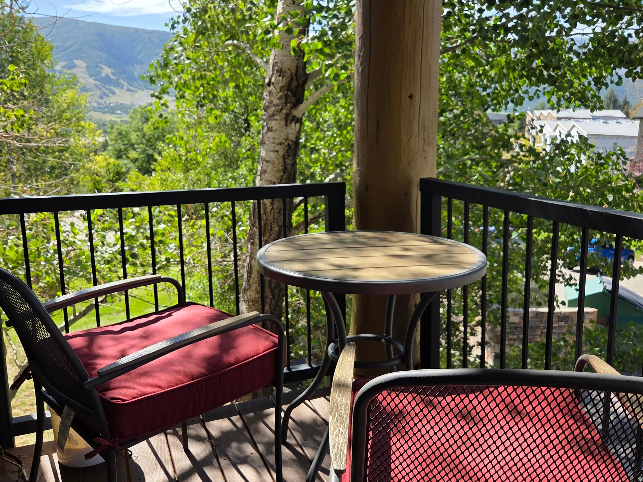 Balcony with wood-finish flooring, black metal railing, and a log post accent