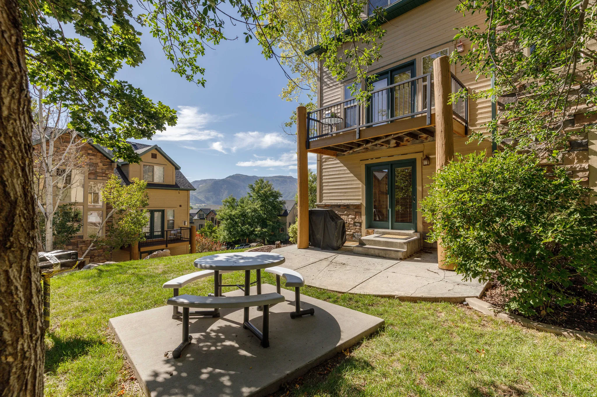 Ground-level patio with direct exterior access, upper-level balcony, and exterior stone accents