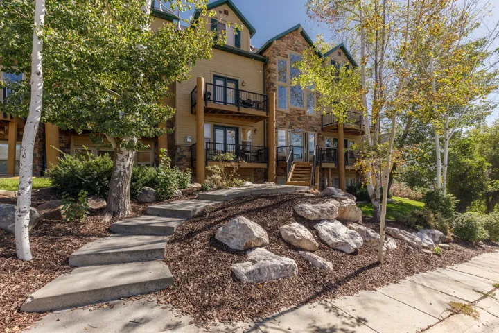 Multi-level exterior featuring stone accents, multiple balconies with black railings, and large window installations