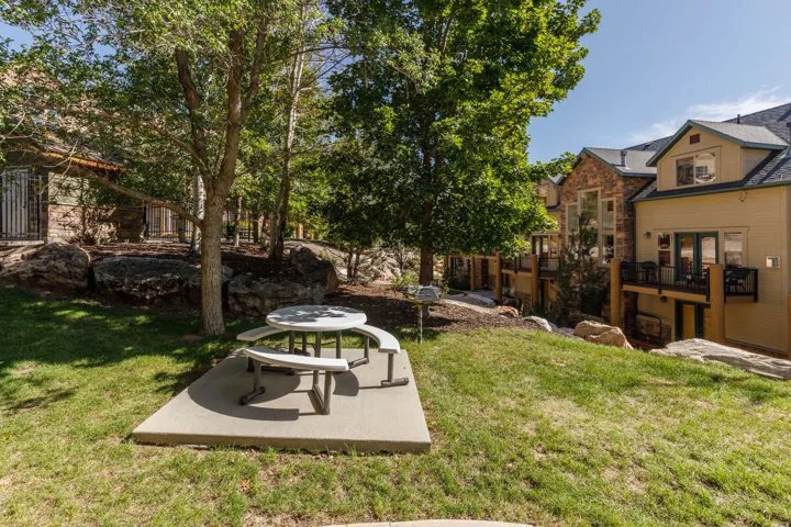 Expansive outdoor space featuring a concrete pad, mature trees, and natural rock landscaping