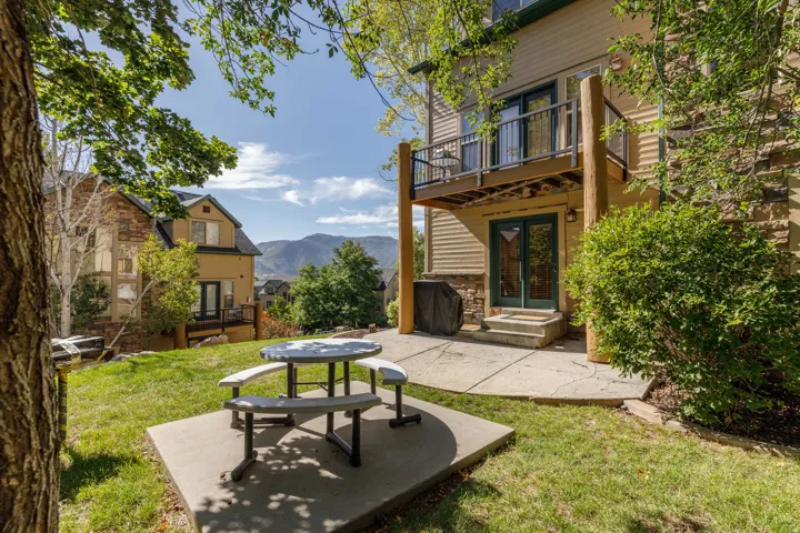Ground-level patio with direct exterior access, upper-level balcony, and exterior stone accents
