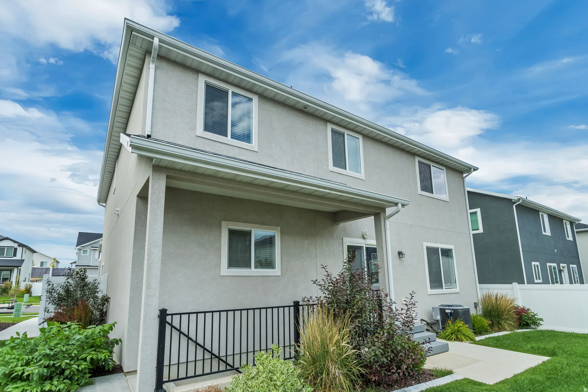 Two-story stucco exterior with white trim windows and a covered patio