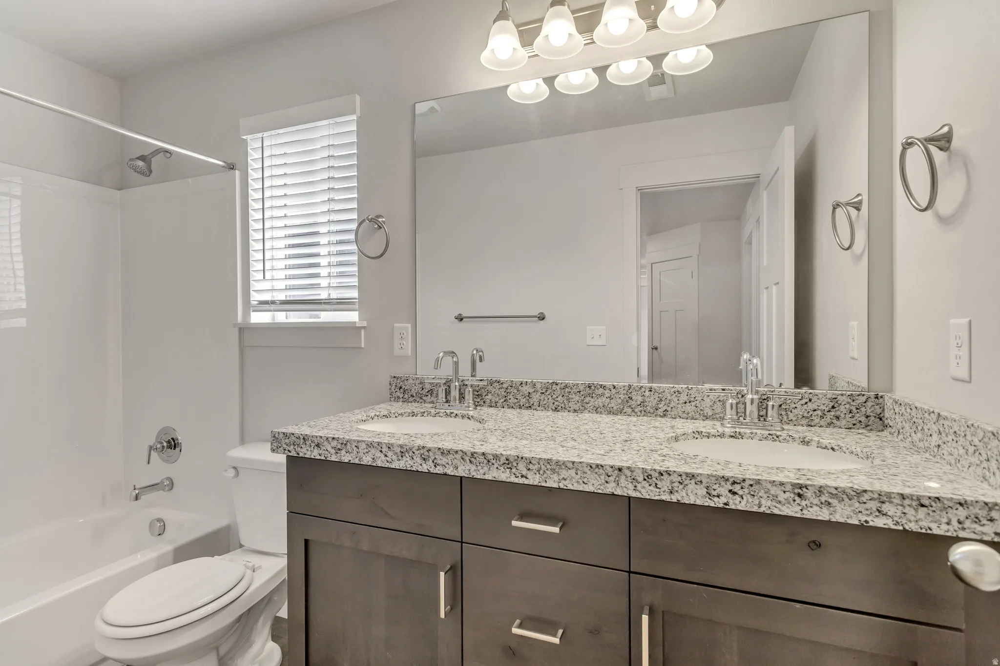 Dual basin vanity with solid surface countertop, wood-finish cabinetry, and brushed nickel hardware