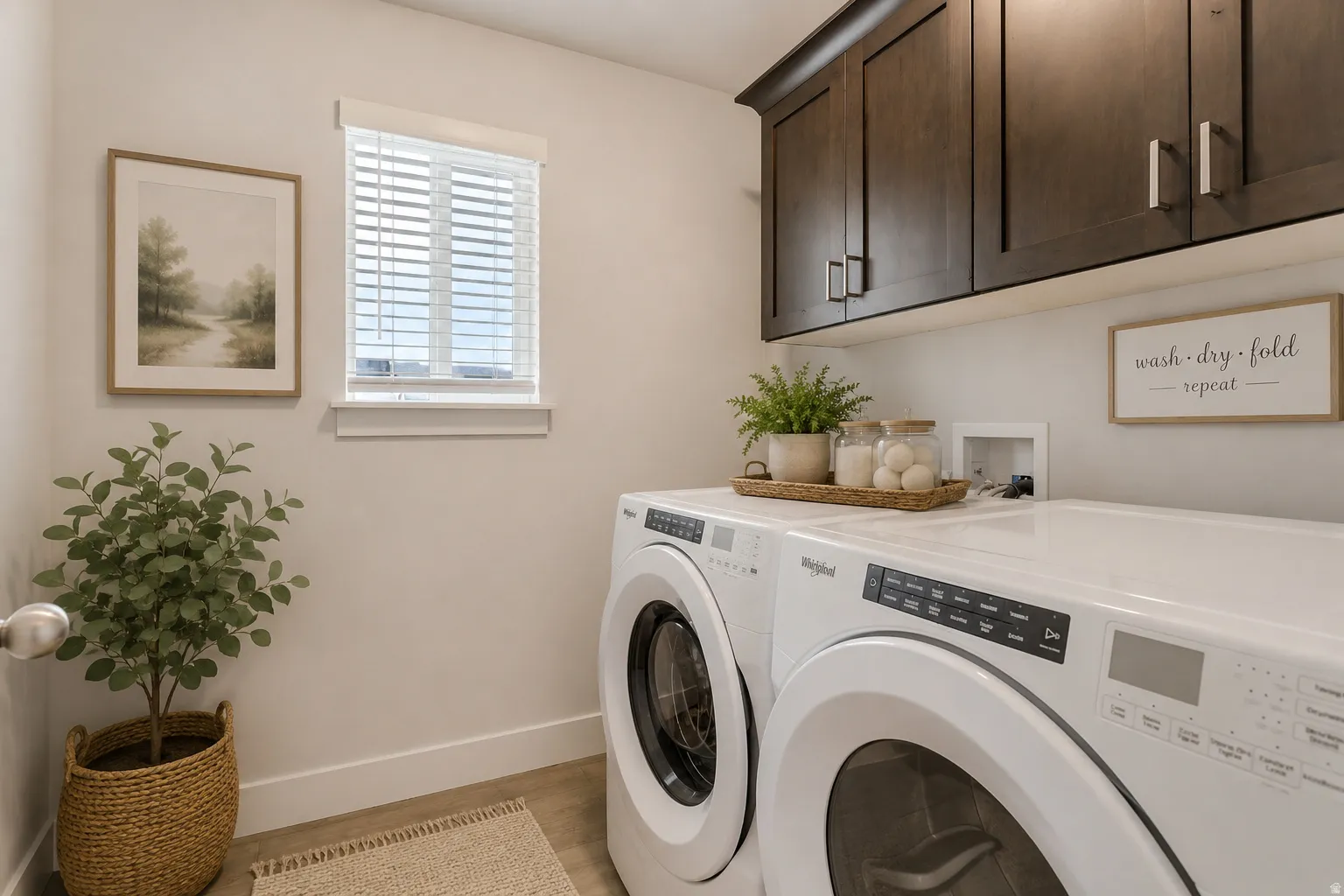 Laundry area featuring wood-finish flooring, dark wood-tone cabinetry with silver hardware, and a window with blinds