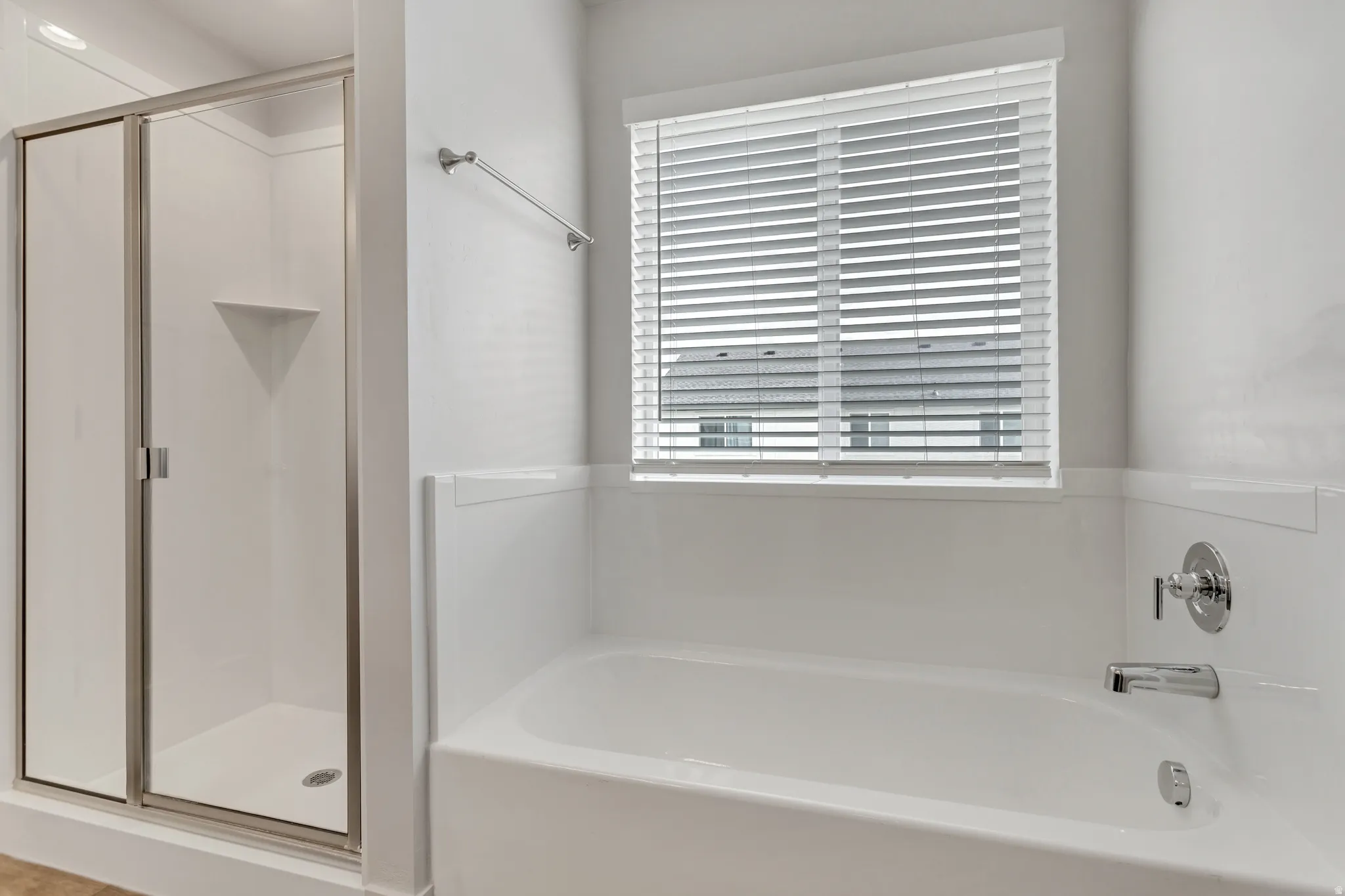 White tub-shower combination with chrome fixtures and an adjacent glass-enclosed shower