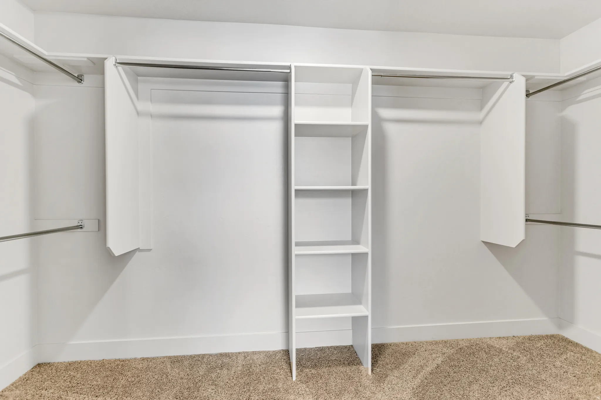 Walk-in closet featuring built-in shelving, multiple hanging rods, and carpet flooring