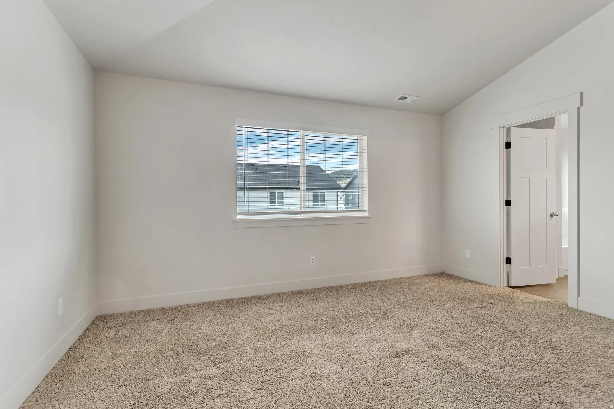 Neutral wall finishes with a window featuring horizontal blinds