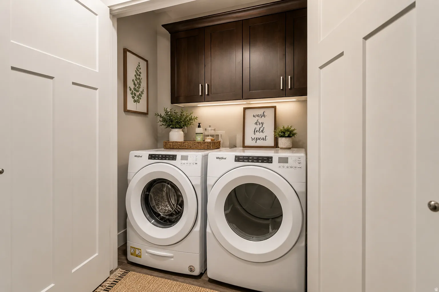 White front-load washer and dryer pair with dark wood-finish cabinetry