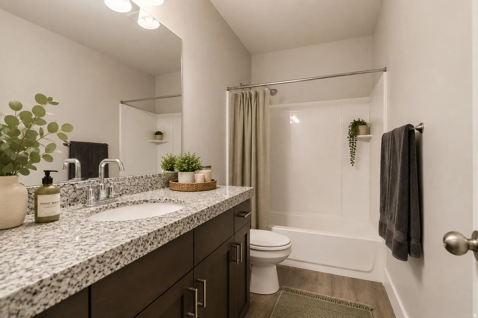 Bathroom featuring a wide vanity with a single basin sink, granite-finish countertop, dark wood-finish cabinetry, and contemporary chrome hardware