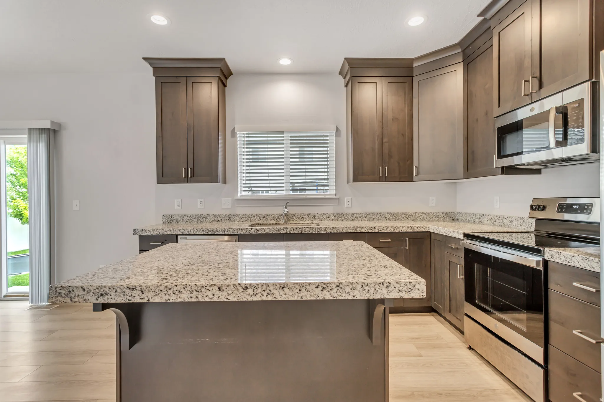 Kitchen featuring wood-finish cabinetry, granite countertops, stainless steel appliances, and a central island