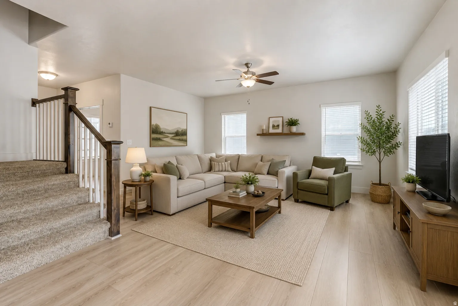 Open-concept living area with wood-finish flooring, multiple windows with blinds, and a ceiling fan