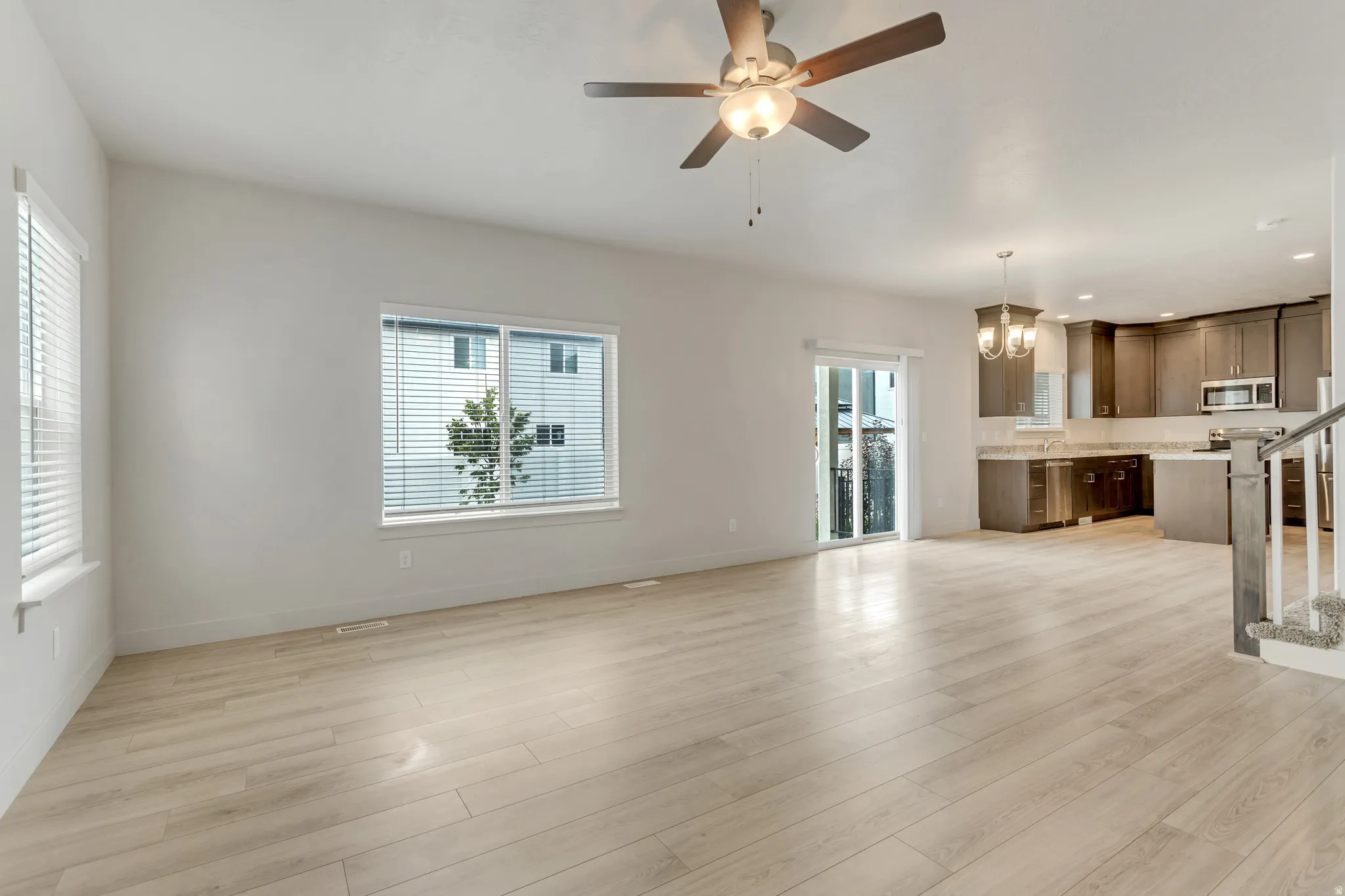 Open-concept living space with light wood-finish flooring, a ceiling fan, and sliding glass door access