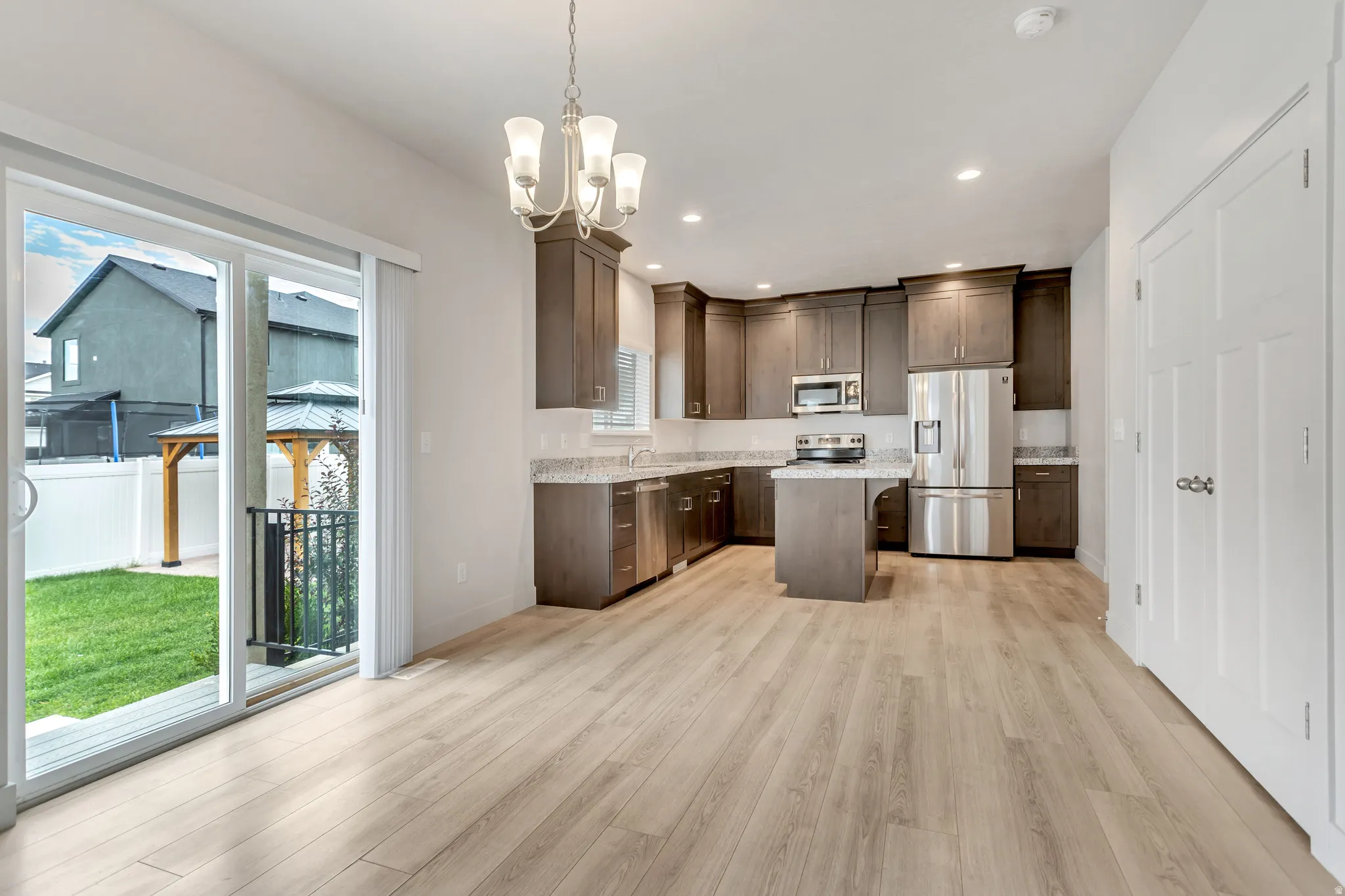 Open-concept kitchen and dining area featuring wood-finish flooring, recessed lighting, and a sliding glass door to the exterior