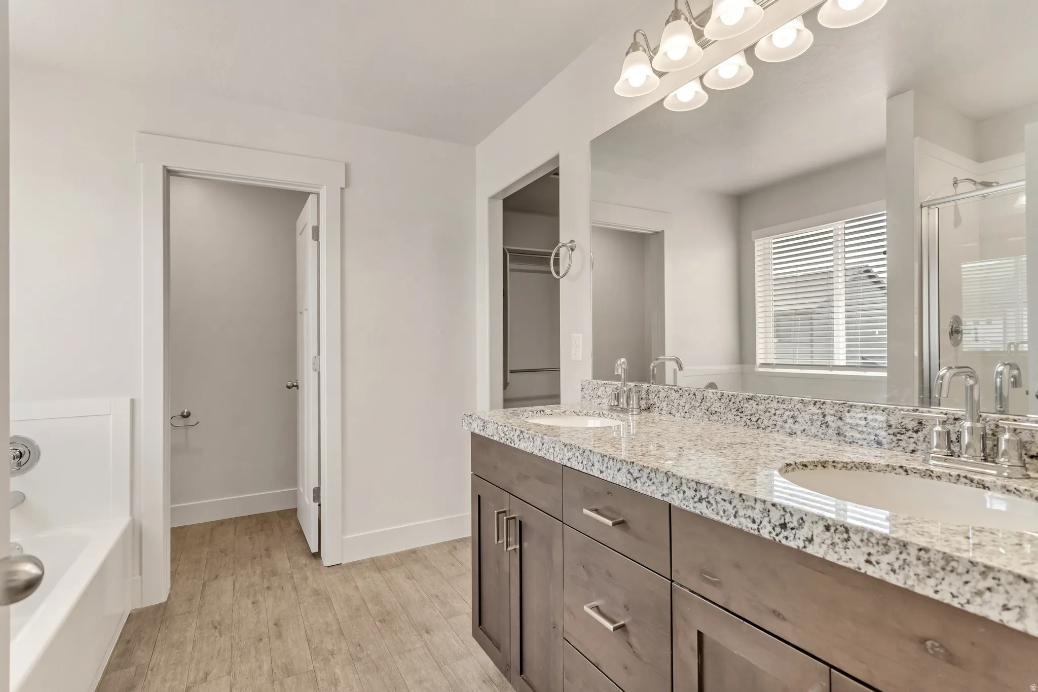 Dual vanity with stone-finish countertop, wood-finish cabinetry, and polished chrome fixtures
