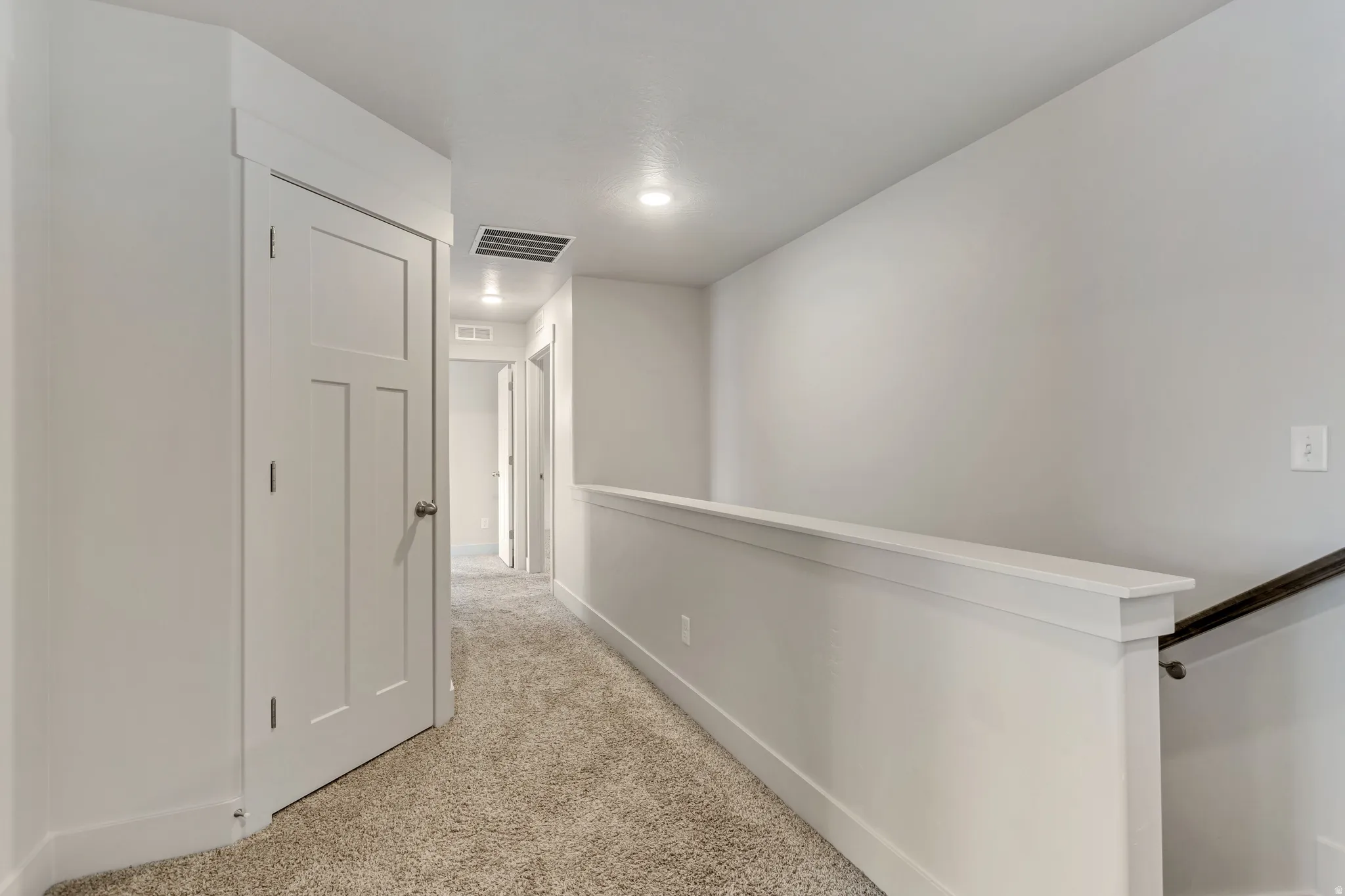 Carpeted hallway with flush-mount lighting, contemporary panel doors, and a partial wall with a cap