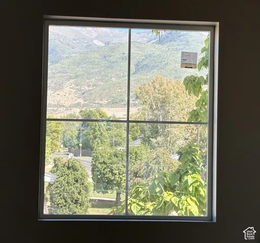 Large window with grid muntins showcasing a mountain backdrop and mature trees