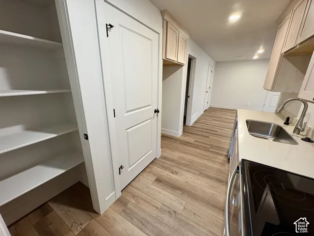 Kitchen featuring wood-finish flooring, light wood cabinetry, white countertops, recessed lighting, and a walk-in pantry with built-in shelving