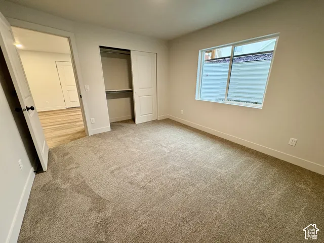 Neutral-toned carpeted flooring, sliding closet door, and large rectangular window