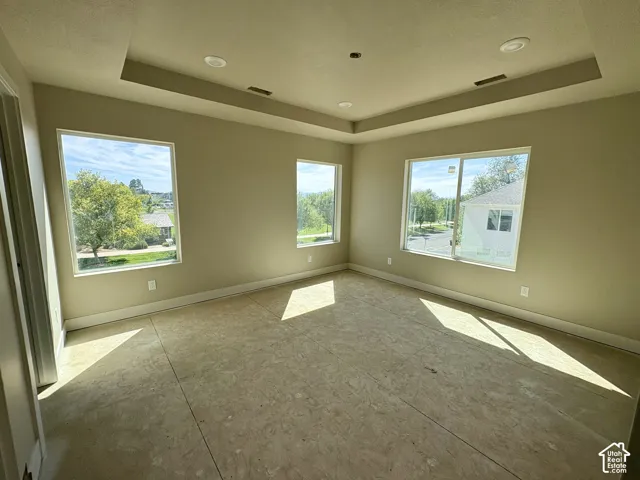Tray ceiling with recessed lighting, multiple windows, and a neutral wall color