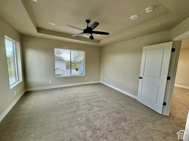 Room featuring a tray ceiling, wall-to-wall carpeting, recessed lighting, and a multi-blade ceiling fan