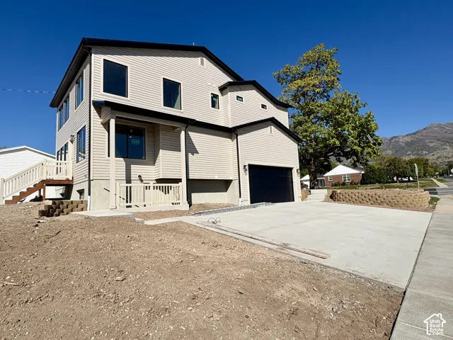 Two-story residence featuring light-toned siding, a black roof, and a prominent attached garage with a black door