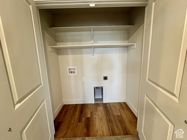 Reach-in utility closet featuring wood-finish flooring, dual panel doors, and two levels of built-in shelving