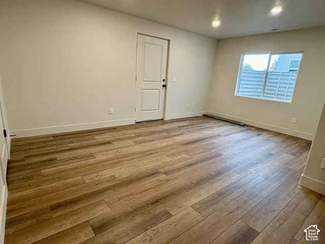 Interior space featuring wood-finish flooring, recessed lighting, a single-panel interior door, and a sliding window