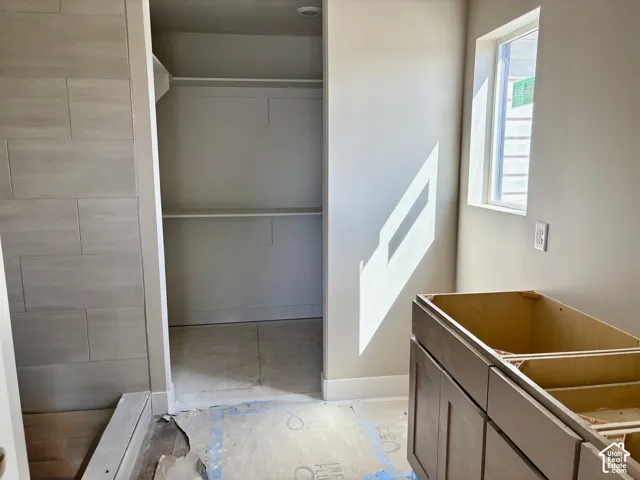 Recessed lighting, built-in shelving, tiled shower surround, framed window, and wood-finish vanity base