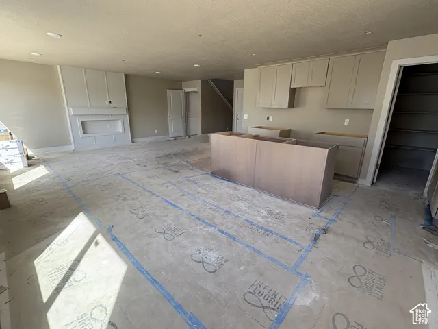 Built-in fireplace with detailed trim work, recessed lighting, neutral wall tones, and unfinished kitchen cabinetry