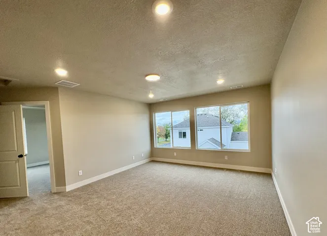 Neutral-toned interior room featuring wall-to-wall carpeting, recessed ceiling lighting, and large slider windows