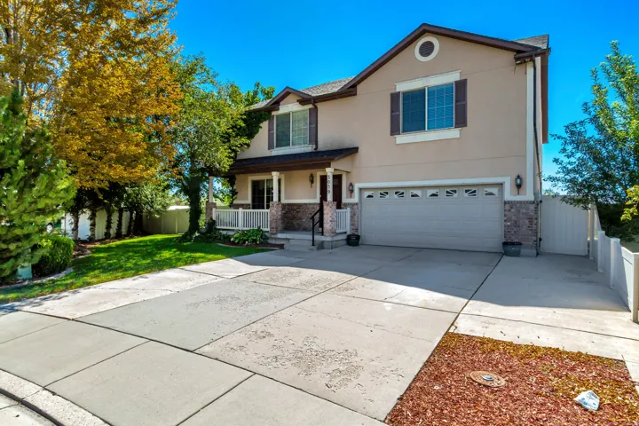 Two-story exterior with stucco siding and brick accents, covered front porch, attached garage, and a concrete driveway