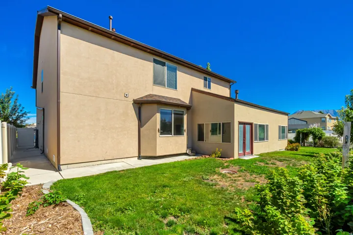 Two-story stucco exterior with multiple windows, a ground-level bay window, and a dedicated side walkway