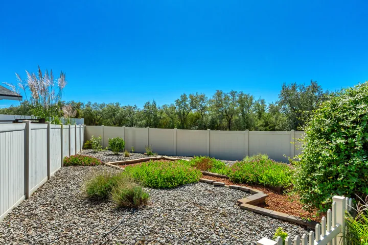 Landscaped backyard featuring gravel ground cover, raised garden beds with wood edging, and established plantings