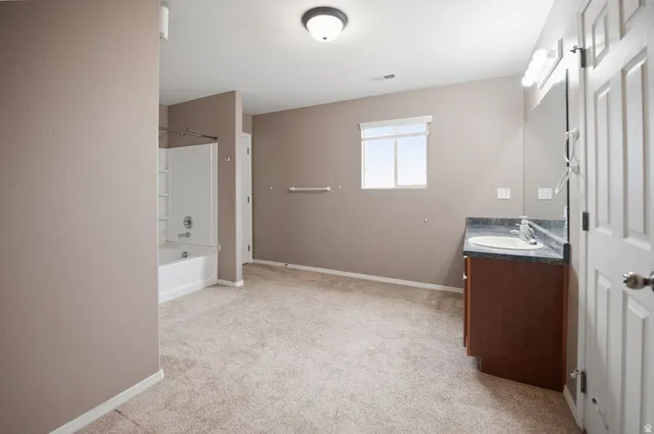 Spacious bathroom featuring a single vanity with a dark countertop, white oval sink, and chrome faucet