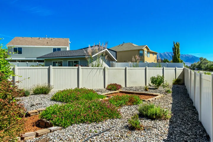 Xeriscape landscaping with gravel ground cover, established plantings, and a privacy fence