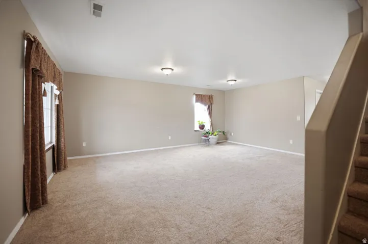 Expansive carpeted room with multiple windows, neutral wall tones, and ceiling-mounted light fixtures