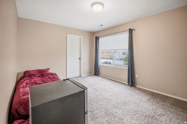 Neutral wall paint, textured carpeting, window with blinds, and ceiling-mounted light fixture