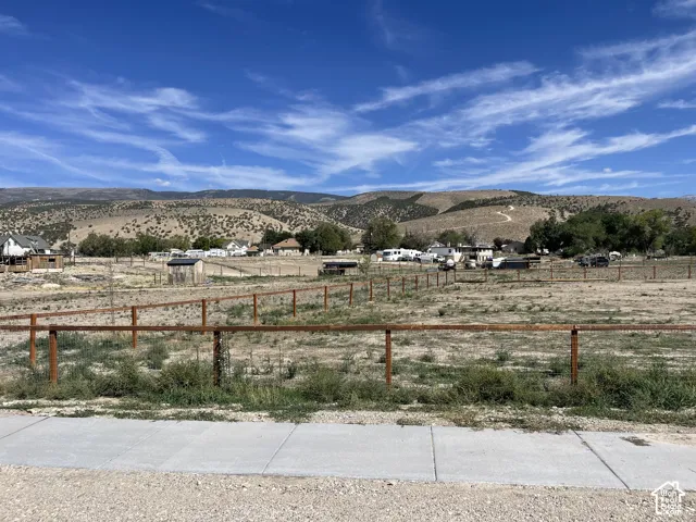 Expansive lot featuring a perimeter fence and concrete sidewalk