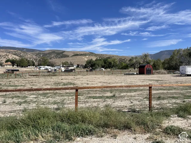Expansive fenced lot featuring a red storage shed and distant mountain scenery