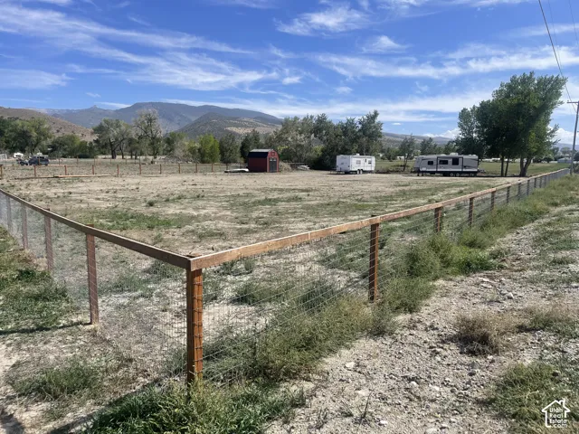 Fenced property with a red shed and distant mountain scenery