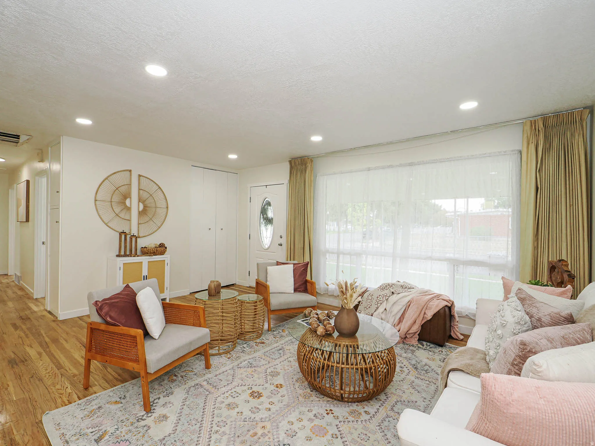 Recessed ceiling lighting, wood-finish flooring, and a large window with privacy sheers