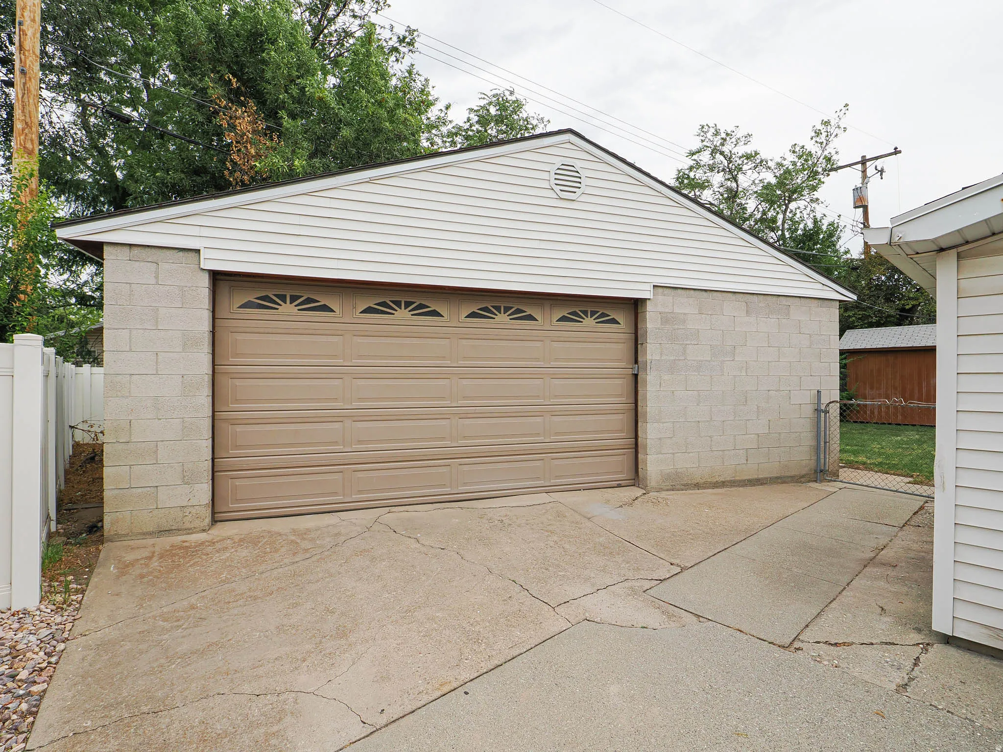 Detached garage with a paneled door, block foundation, and light-colored siding