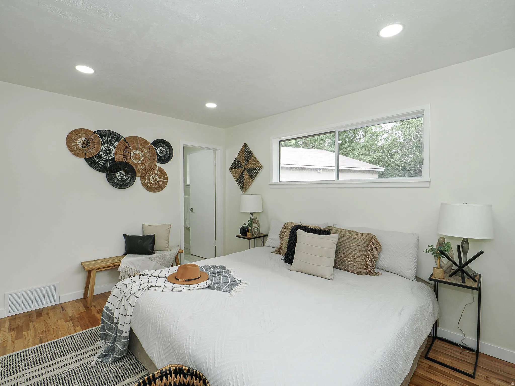 Recessed ceiling lighting, wood-finish flooring, white walls, and a rectangular window