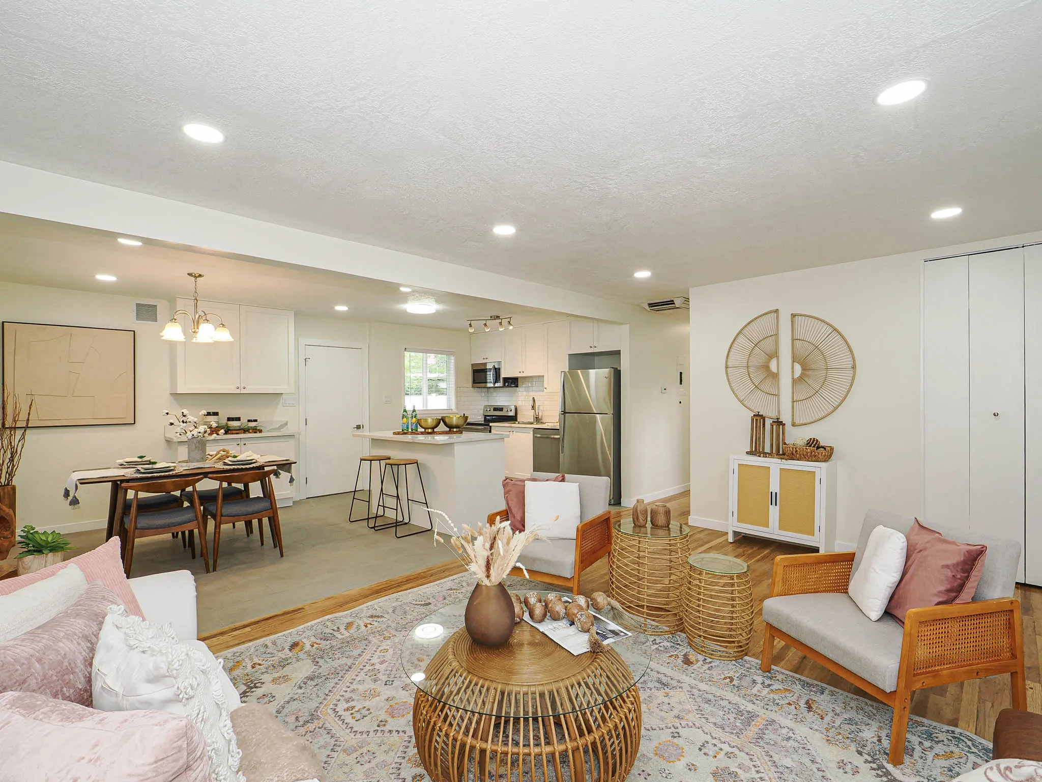 Recessed lighting illuminates the open-concept design, featuring wood-finish flooring and a kitchen island with seating