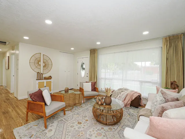 Recessed ceiling lighting, wood-finish flooring, and a large window with privacy sheers