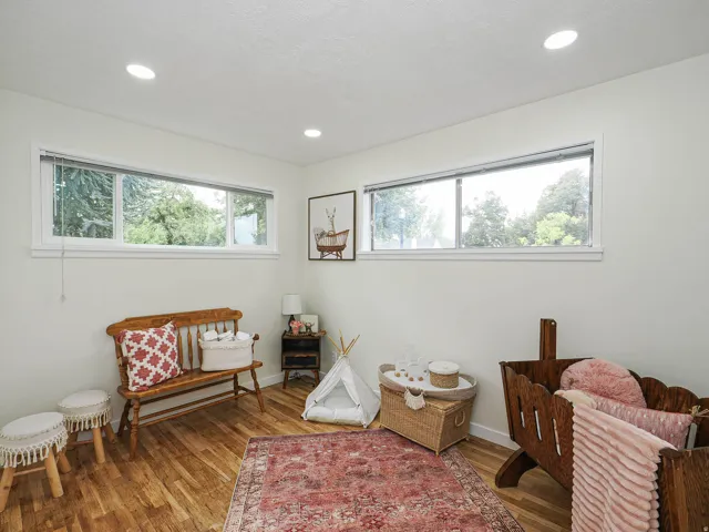 Recessed lighting illuminates wood-finish flooring and multiple windows with blinds