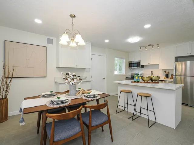 White shaker cabinetry, stainless steel appliances, white subway tile backsplash, recessed lighting, and a kitchen island with a light-toned countertop