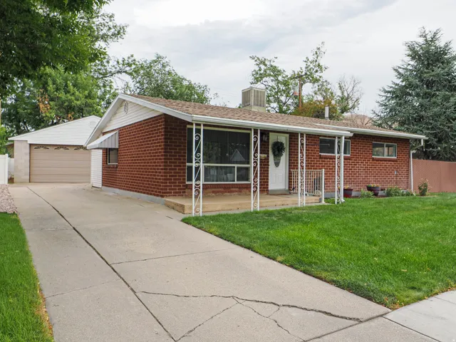 Brick exterior with a covered porch, an attached carport, and a detached garage